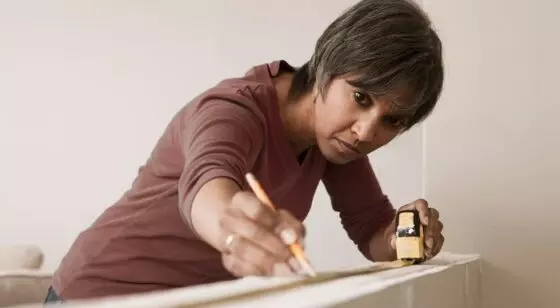 A woman measuring a beam in her house
