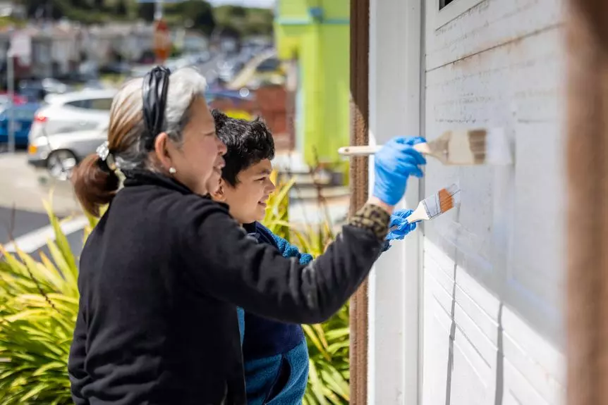Grandson helping his grandmother repaint the garage door at her home.